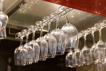 empty wine glasses are hanging on stainless steel bar rack in kitchen room.
