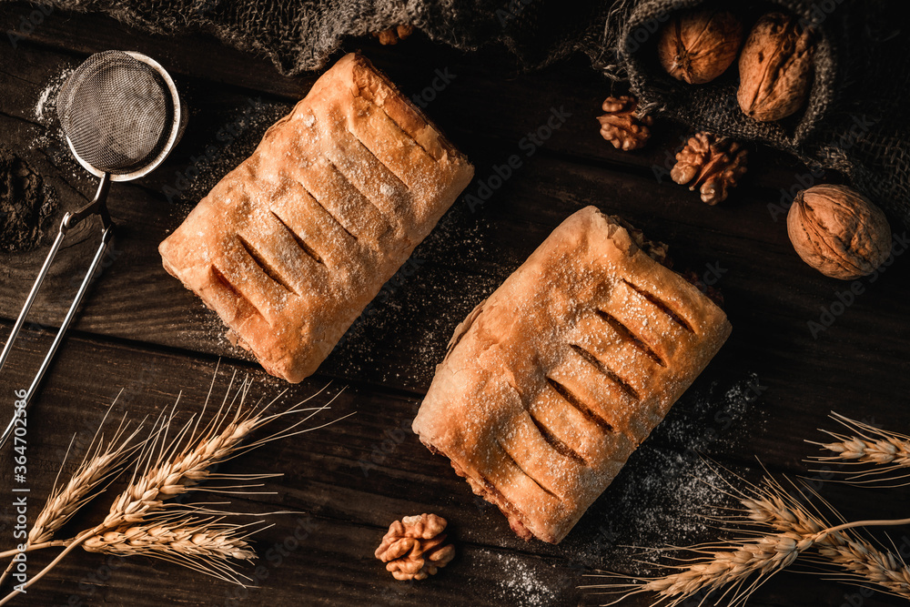 Wall mural Freshly sweet puff pastry buns with jam on slate sackcloth background with wheat spikelets and walnut. Pastries and bakery, top view