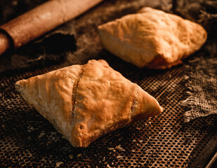 Fresh puff pastry buns on metal oven tray background with rolling pin. Pastries and bakery, close up