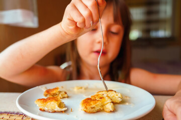 Young beautiful girl eating cheesecakes for breakfast. Selective focus.