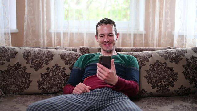 A man sits on a couch and talks through a mobile video call