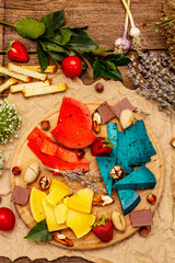 Cheese plate. Assorted multicolored hard Dutch cheeses. Blue and red pesto, aged gouda