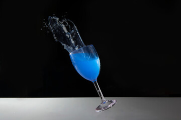 Blue splash water out of a glass on black background.