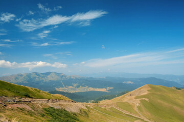 Obraz premium View of the green heels covered with green grass and trees