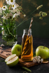 Composition with apple juice in a glass bottle with green apples and wildflowers. Detox, clean food, vegetarian, vegan, fitness or healthy lifestyle concept.