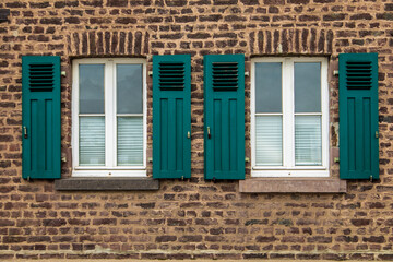 old white framed windows on mediterranean house out of brick walls with green shutters
