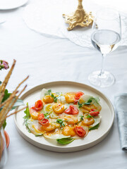 Scallop with ginger and micro greens. Bright seafood platter decorated with stalks of green peas. Served on a white ceramic plate. White tablecloth. Beautiful table setting. Fish restaurant.