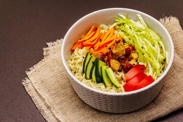 Traditional Korean noodle bowl with smoked chicken, fresh sliced vegetables and sesame seeds
