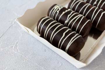 Chocolate rum balls cake decorated with white glaze on paper substrate and light grey background with copy space. Sweet chocolate potato cakes.
