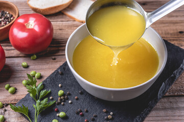 Chicken soup bouillon in a bowl on rustic wooden table