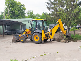 Wheeled excavator with a metal bucket for digging trenches