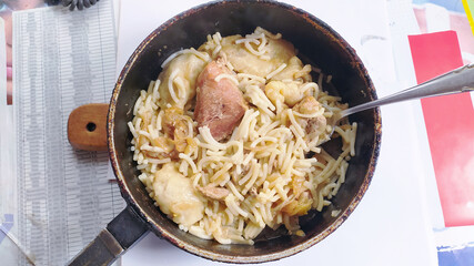 Frying pan with prepared food meat and pasta