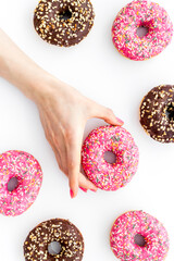 Hand holding donut with icing and sprinkles. Flat lay, top view