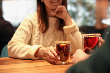 Lovely couple with tasty mulled wine at table in cafe, closeup