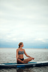 Fototapeta na wymiar Woman practicing yoga on the paddle board in the morning