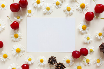 Paper, camomiles, cherry berries and fir cones on a ivory background. Top view, Mock up, Summer flat lay, place for text.