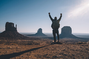 Hipster guy feeling freedom looking at beautiful natural landscape in Monument Valley, male traveler wanderlust excited with achievement of getting to viewpoint exploring wild environment of America