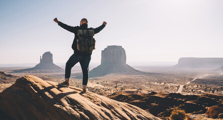 Male traveler with rucksack feeling excited with beautiful nature in Monument valley standing on...