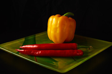 red and yellow peppers on a colored plate with a black background