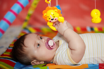 4-Month-Old Baby girl playing with toys. Girl pulling hand for a toy. The kid plays the rattle