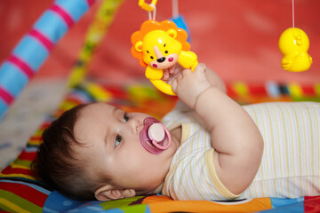4-Month-Old Baby girl playing with toys. Girl pulling hand for a toy. The kid plays the rattle