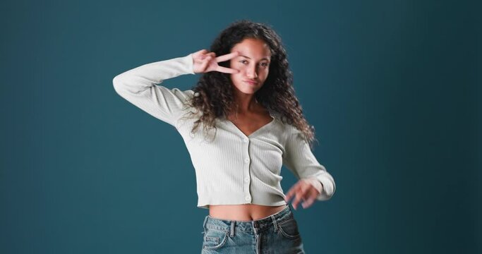 Portrait of beautiful brunette young woman with curly hair, dancing and having fun on blue screen