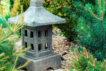 Ornamental stone lantern with among fresh green plants japanese design, outdoor garden stone statue decoration