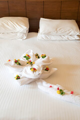 Hotel room interior indoor, apartment, bed with white sheets and flower towel for guests, vacation relaxing concept