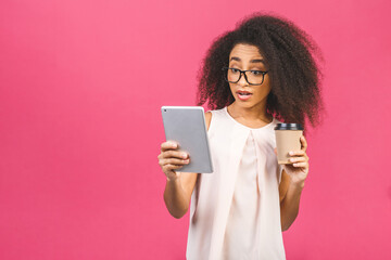 Young american student girl with curly african hair holding digital tablet and coffee or tea over isolated pink background with copy space for text, logo or advertising.