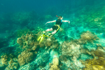 Naklejka na ściany i meble Man snorkeling in diving suit in coral reef of Surin Islands, Andaman Sea, North of Phuket, Phang Nga in Thailand. Swimming in Ko Surin Marine National Park, underwater water sport activity. top view