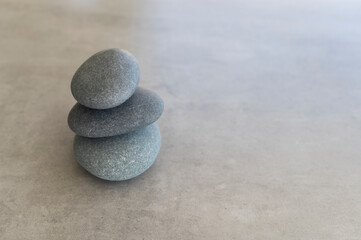 Fototapeta na wymiar SPA concept. Still life Pyramid of grey stones on a ceramic tile background. Copy space for promo text