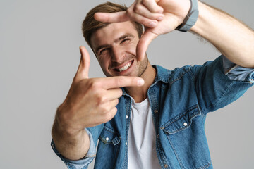 Portrait of cheerful man smiling and making frame gesture on camera
