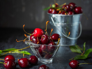 Berry dessert. Cherry in a glass figured vase and a metal bucket of cherries