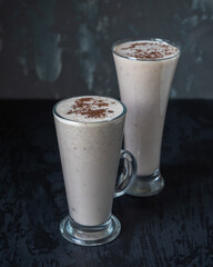 Two tall glass glasses with a milkshake with berries and chocolate