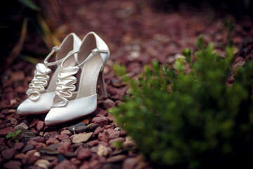 A pair of white elegant bride shoes on a rocks background
