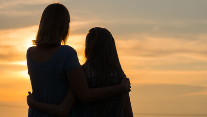 Silhouettes of mother and daughter at sunset