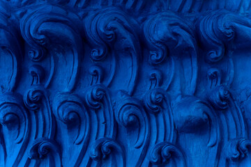 A bas-relief element in the form of sea waves at the base of the Buddha statue in a Buddhist temple. Abstract Indigo background.
