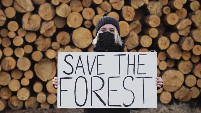ecology concept - save forest poster. young woman eco activist outdoor. deforestation concept, logging, felled timber in the forest. earth. nature, forest, environment
