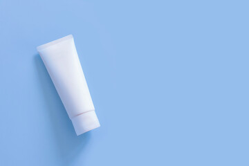 Top view of mockup of white squeeze bottle plastic tube for branding of medicine or cosmetics - cream, gel, skin care, toothpaste. Cosmetic bottle container on a pastel blue background. Minimalism