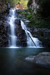Fototapeta na wymiar Waterfall tumbling over a ledge into a beautiful swimming hole below