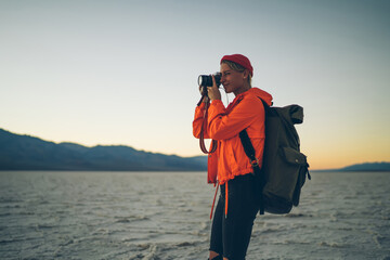 Professional female photographer making picture of panoramic view of landscape in Badwater national park,young woman hiking in wild lands with unique geological environment of dry lake surface.