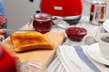 Photo of kitchen table with toasts, fruit jams and knife
