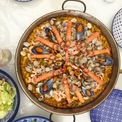 Traditional Spanish seafood paella with with seafood is on the table with different utensils. View from the top.