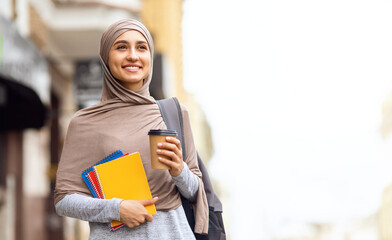 Female student in headscarf having morning coffee before university