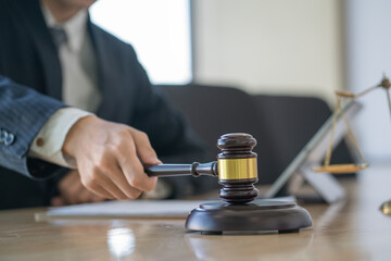 Judge hitting gavel at wooden table.