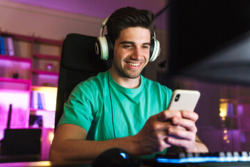 Image of caucasian smiling man using cellphone playing video game