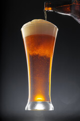 Beer pouring into glass on black background