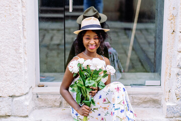 Pretty african woman sits on stairs outdoor.