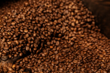 Blured Photo. Fresh Roasted Natural Coffee Beans Cascading out of Industrial Coffee Bean Roaster Machine Inside the Coffee Shop