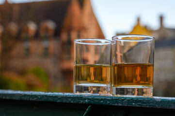 Scotch single malts or blended whisky spirits in glasses with old houses of Edinburgh on background, Scotland, UK